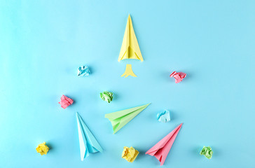Different colorful paper airplanes and crumpled paper balls on blue gradient background. Creativity...