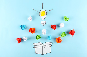 Thinking outside the box concept. Drawn paper lightbulb as a metaphor for fresh idea on blue gradient background. Close up, copy space, top view, flat lay.