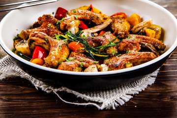 Roast chicken wings with vegetables served on frying pan