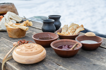 Shrovetide, pancake week.  Fried pancakes with jam and sour cream in a pancake week in a rustic style on the street.
