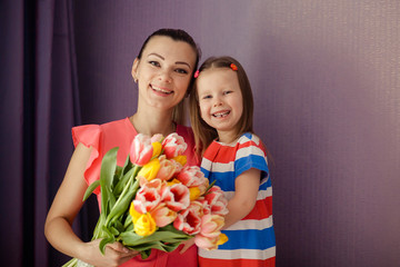 Happy mother's day! daughter congratulates mom and gives a bouquet of flowers to tulips. Happy children and parents, family.