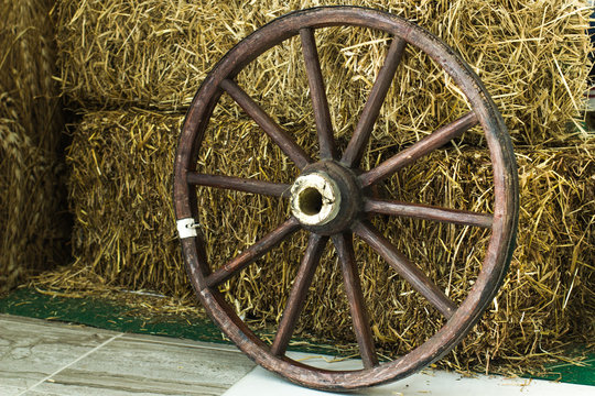 wooden wheel from a cart on a hay background