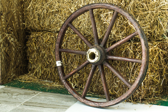 wooden wheel from a cart on a hay background