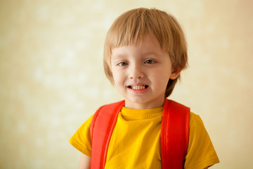portrait of a happy cute blond child 4-5 years old with a backpack