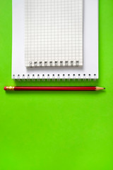 school spiral notebook and pencil with pen on green background