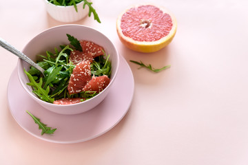 Fresh citrus salad with arugula, grapefruit and sesame seeds on pink background. Selective  focus. Raw vegetarian spring detox food.