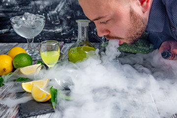 man lets out steam from a mouth on a table served with limoncello