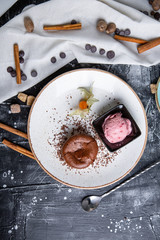 Chocolate lava cake Molten with ice cream on plate and cappuccino. Balls of ice cream in cup . Dark black background.