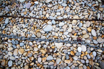 Rusty chain laid on pebbles, Chesil beach, Weymouth, Dorset.