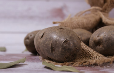 Potatoes on a light background, next to a potato sack