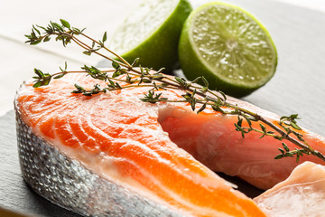 Shiny raw red fish with thyme and limes next to it