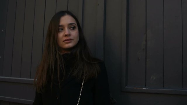 Suspicious young woman standing near big gate of luxury house, illegal business