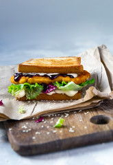 Katsu Sando at wooden desk - food trend japanese sandwich with chicken cutlet, cabbage and tonkatsu sauce. Japanese cuisine