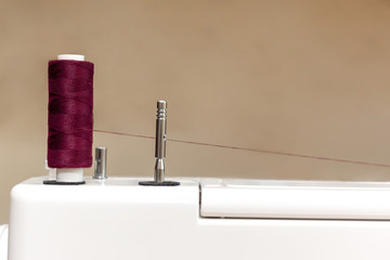 thread spool on a sewing machine close-up on the brown backgound