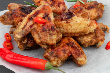 Baked chicken wings with and sweet chili sauce on  wooden board over dark background