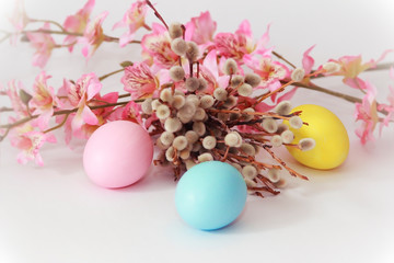 pink yellow blue eggs against a background of willow and flowers for the Easter holiday