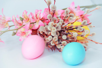 pink yellow blue eggs against a background of willow and flowers for the Easter holiday