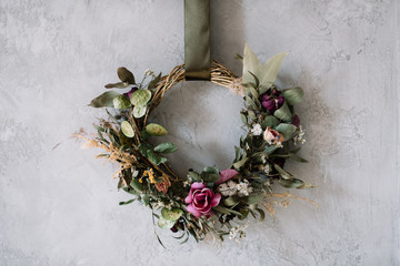 Beautiful hand made everlasting dry wreath made of roses, wheat and eucalyptus on the grey wall...