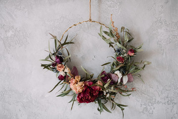 Beautiful hand made everlasting dry wreath made of roses, hydrangea flowers and eucalyptus on the grey wall background - 250847864