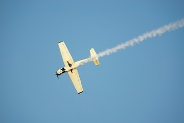 Airplane with Smoke Against Blue Sky in Switzerland.