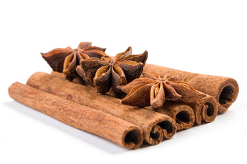anise stars laying on cinnamon sticks isolated on white background.