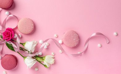 Pink macarons with pearls and white roses for womens day on a cleare pink background with blank space for design elements and text