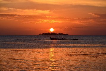 Sunset on the island with fishing boat silhouette