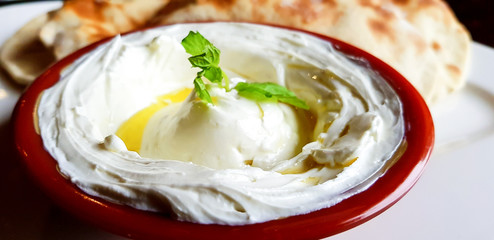 A bowl of Labneh, popular arab yoghurt cream cheese dip, with mint leaves