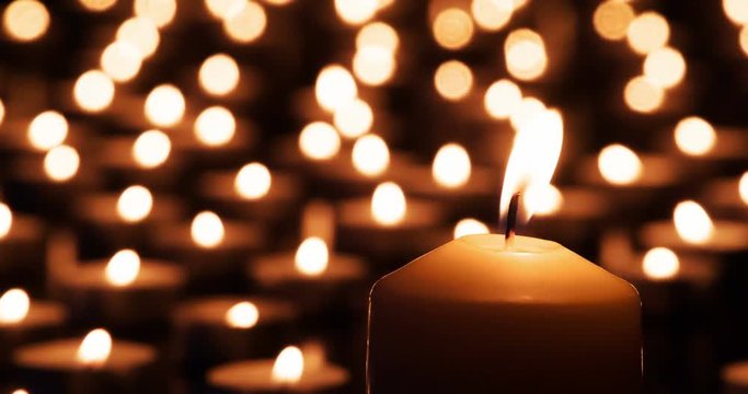 Candle and Small Lights in the Background.  A large candle close up against the background of many small lights