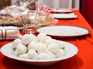 plate of small fresh Italian mozzarella, for dinner, on the red table at Christmas time