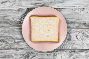 White bread toast on pink plate on wooden background