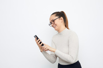 Naklejka premium happy young woman with mobile phone in hand smiling