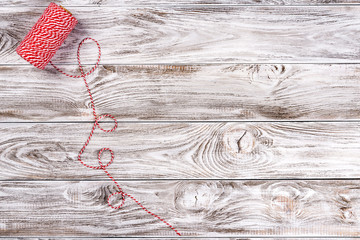 Christmas decorative red and white thread in light wooden background. Space for text.