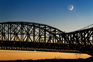 The Pont du Quebec and the St Lawrence River at dusk from Parc de la Marina-de-la-Chaudière, St-Romuald with a crescent moon with earthshine behind