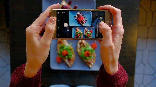 Top view - Woman's hands using a smartphone take pictures of delicious food. 4k. Fresh beautiful waffles with spinach, cherry tomatoes and dessert with spicy pear.
