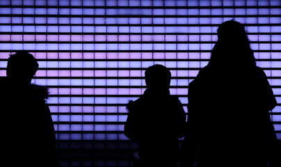 Silhouettes of three children in front of a purple lit wall