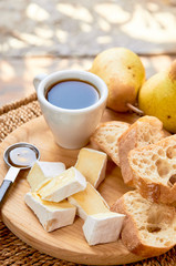 Fototapeta na wymiar Rustic breakfast. Espresso and cheese plate. Brie, pears, walnuts, baguette bread