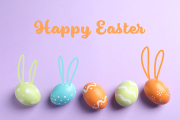 Set of colorful eggs with bunny ears on color background, top view. Happy Easter