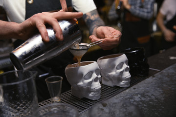 Bartender pouring tasty cocktail at counter in nightclub, closeup
