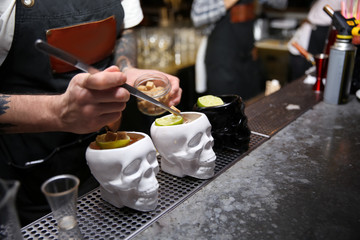Bartender preparing tasty cocktail at counter in nightclub, closeup