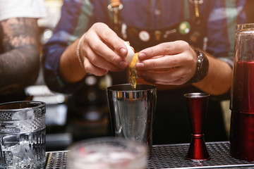 Bartender preparing tasty cocktail at counter in nightclub, closeup