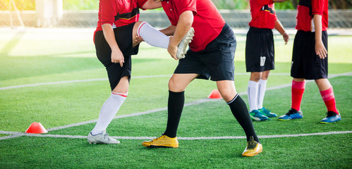 boy soccer players stretch muscles with coach