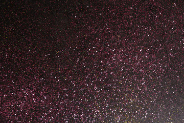 Sparkling pink glitter on dark background, top view