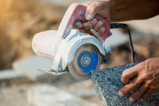 worker cutting granite stone with an diamond electric saw blade and use water to prevent dust and heat