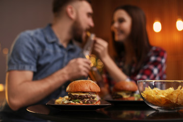Happy couple having lunch in cafe, focus on burger