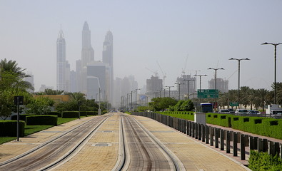 The tracks of the Dubai RTA Trams leading towards the skyline of the Dubai Marina.  The Dubai tram is the latest addition to the city's transport network, opening up in November 2014.