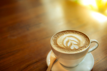 Coffee Espresso. Cup Of Coffee with latte art foam on wood table near window with light shade.