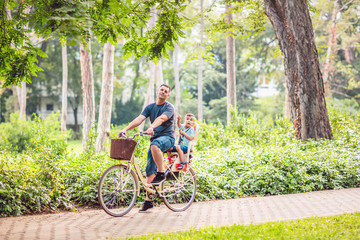 Obraz premium Smiling father with boy on bicycles having fun in park. .