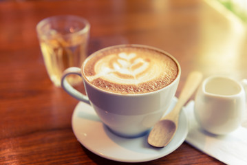 Coffee Espresso. Cup Of Coffee with latte art foam on wood table near window with light shade.
