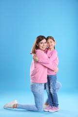 Happy woman and daughter in stylish clothes on color background